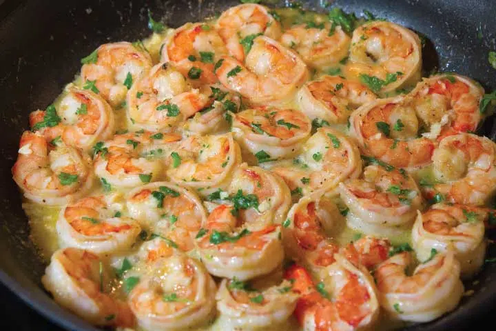 A pan of shrimp with sauce and green onions.