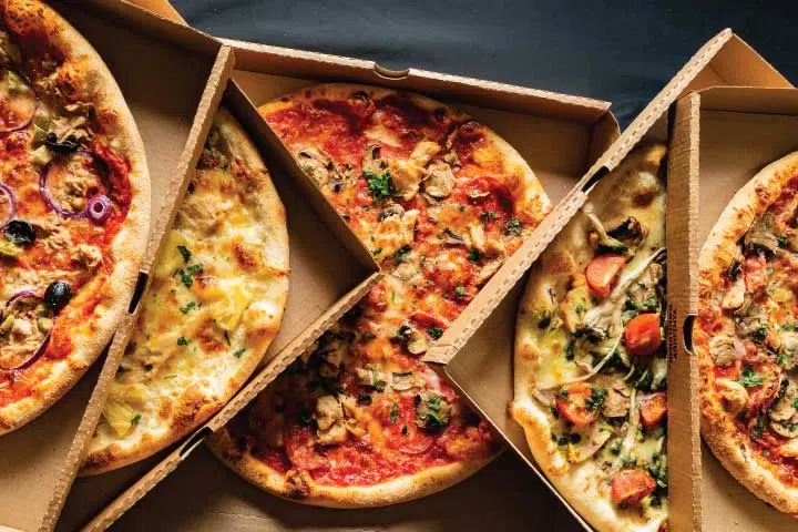 A close up of three different pizzas in boxes