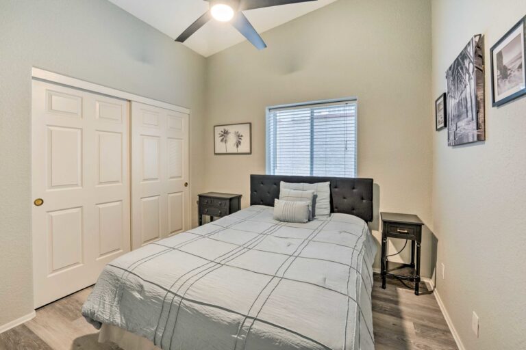 A bedroom with a bed, two nightstands and a window.