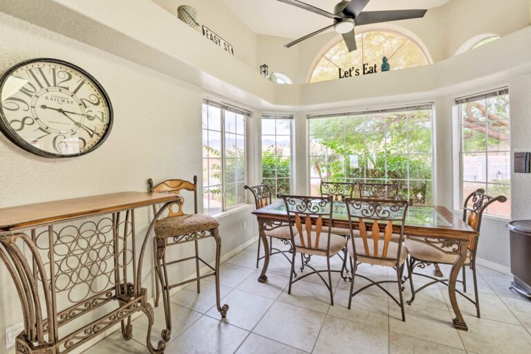 A dining room with a table and chairs, a clock on the wall.