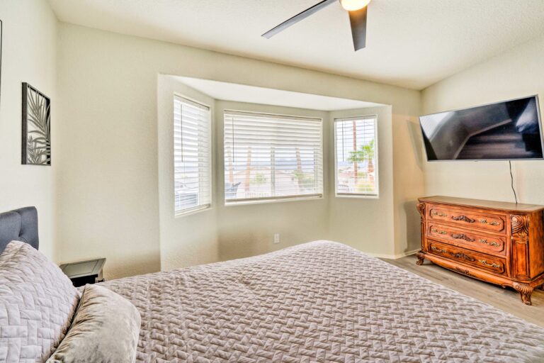 A bedroom with a bed, dresser and tv.