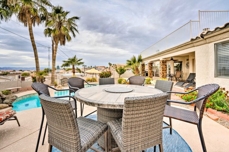 A patio table with chairs and palm trees in the background.