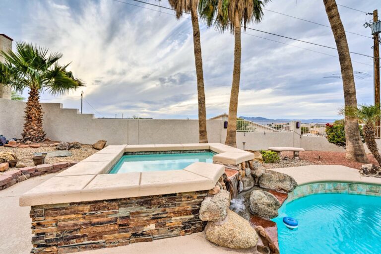 A pool with a rock wall and palm trees