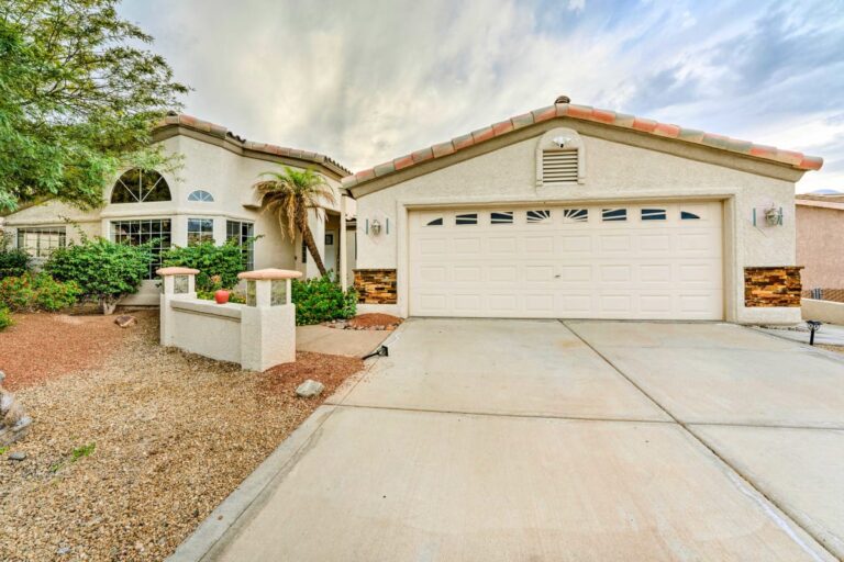 A white house with a driveway and palm trees.