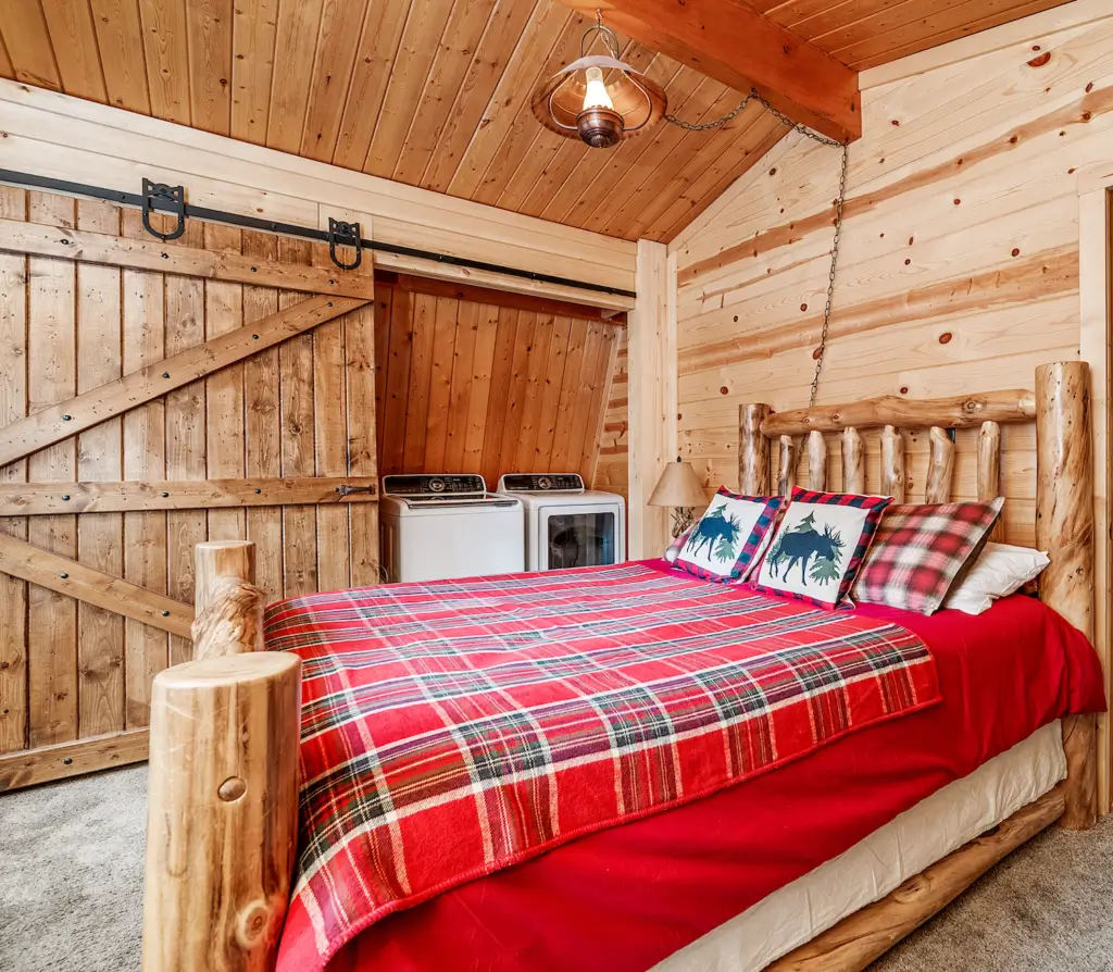 A bed room with a red blanket and pillows