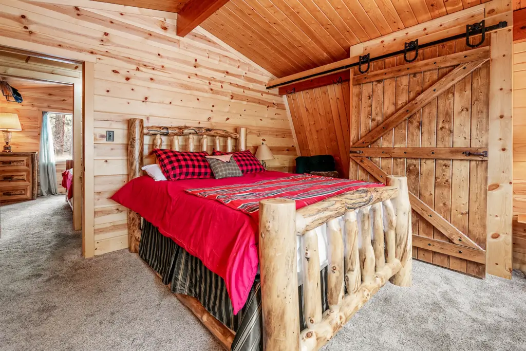 A bed room with a wooden bed and red blanket